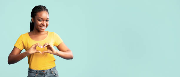 istock Black Lady Gesturing Heart Shape Standing On Blue Background 2180300251