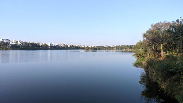 istock Serene lake with distant cityscape under blue sky 2180301088