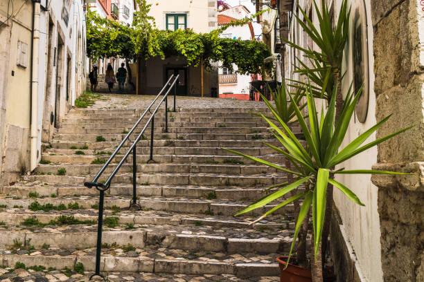 A small pedestrian street in the old town of Lisbon with steps leading up the hill.