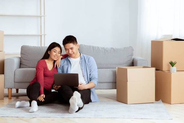 istock Young asian couple using laptop sitting on floor 2180307993