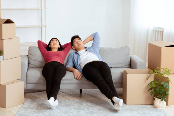 istock Tired asian couple lying on new sofa and sleeping 2180307997