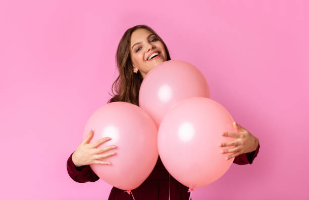 istock Playful Young Lady Cuddling Three Balloons And Sincerely Smiling 2180309760