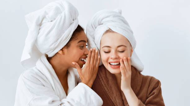 istock Afro girl in bathrobe sharing secrets with her girlfriend 2180314284