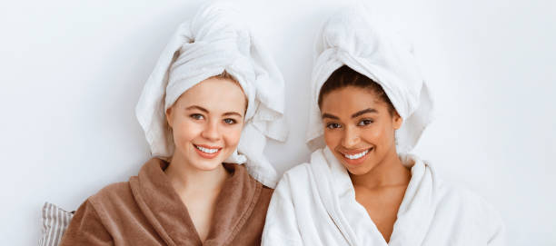 istock Stunning girlfriends in bathrobes sitting on bed and drinking coffee 2180314294