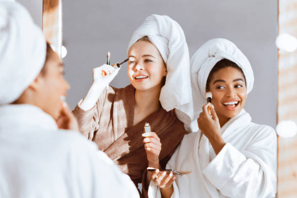 istock Girlfriends in bathrobes getting ready for party, putting make up 2180314398