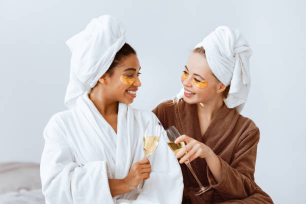 istock Girlfriends trying new beauty product, drinking champagne 2180314417