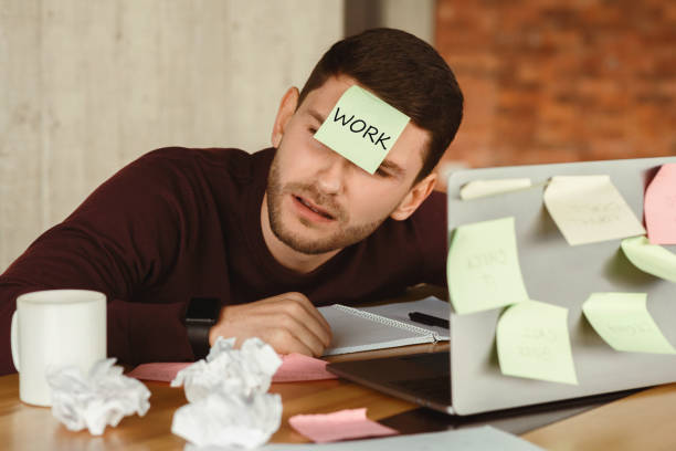 istock Overworked man sleeping tired of office multitasking work indoor 2180316203