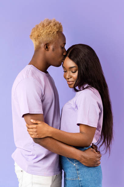 istock Millennial black guy hugging and kissing his girlfriend on lilac background 2180322708