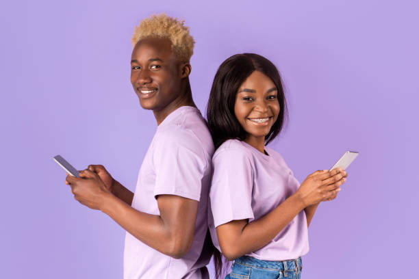 istock Beautiful African American couple with smartphones communicating or using internet on violet background 2180322757