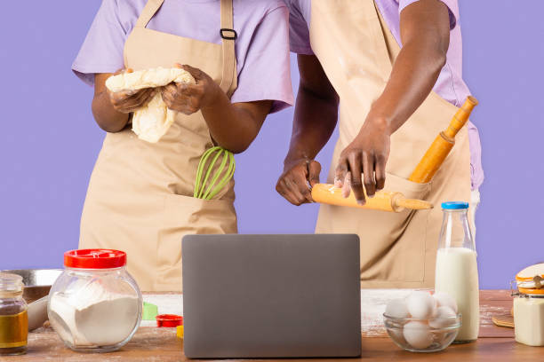 istock African American couple watching online culinary video on laptop while baking, color background 2180322763