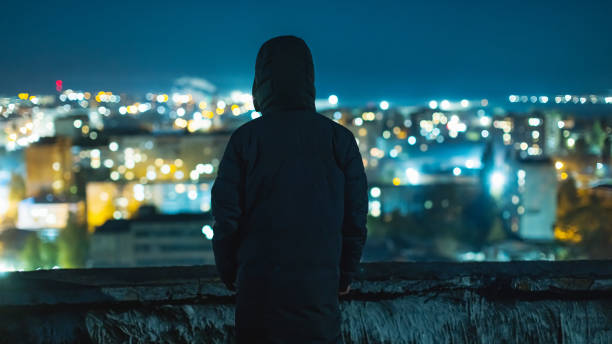 Man silhouette against night city background.