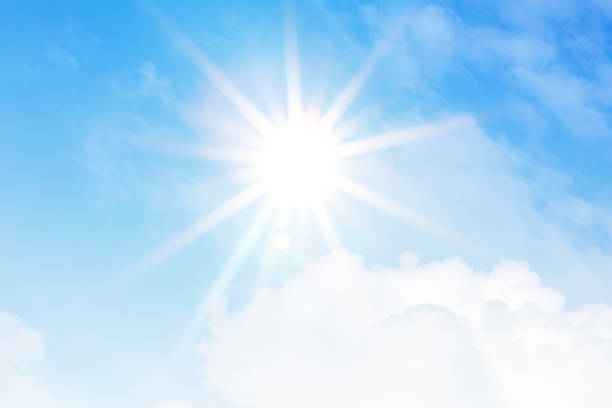 Bright sun with beautiful beams on a blue sky with clouds.
