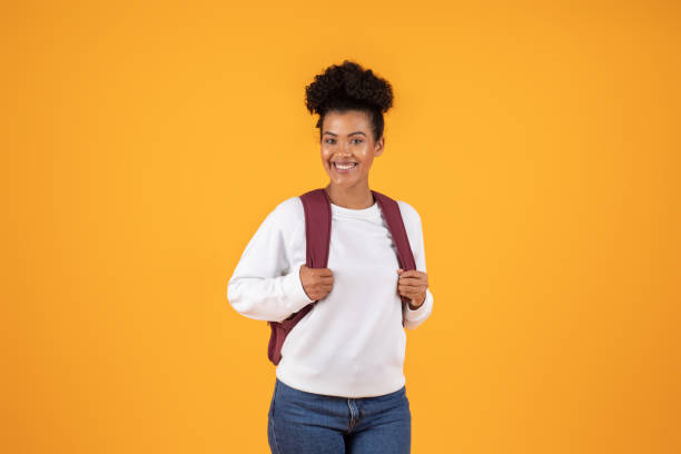 istock Young woman with backpack smiling against a bright yellow background 2180324443