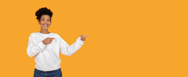 istock Person in white sweater smiles and gestures against an orange backdrop 2180324463