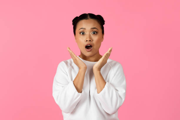 istock Surprised woman with two buns expressing excitement against a pink background 2180326266