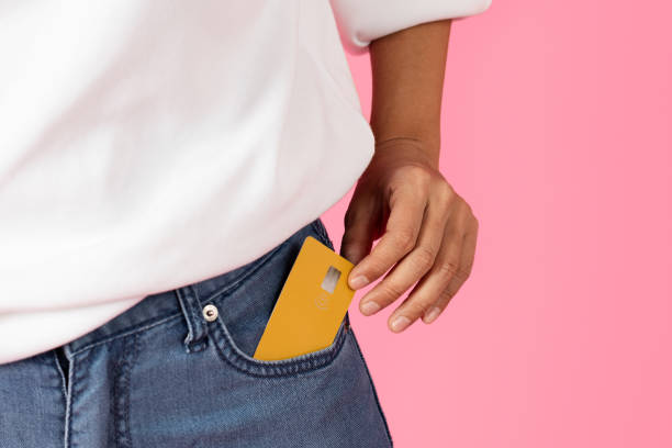 Yellow card in denim jeans pocket on a pink background