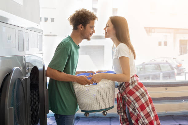 Young couple enjoying a playful moment while doing laundry at home