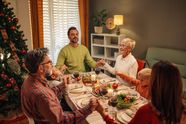 istock Family holding hands and praying before christmas dinner 2180331289