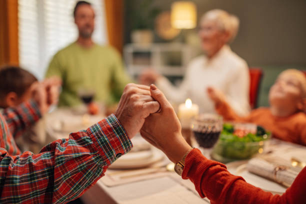 istock Family holding hands while praying before christmas dinner 2180331290