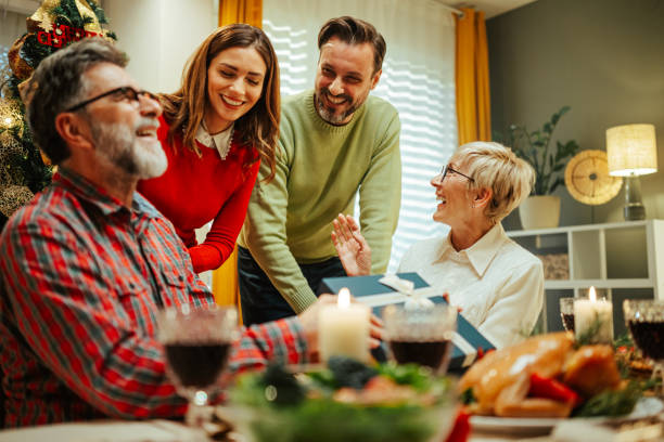 istock Family giving christmas present to grandfather at dinner table 2180331421