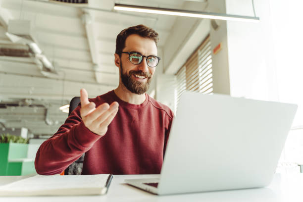 istock Smiling businessman having video call using laptop in office 2180338146