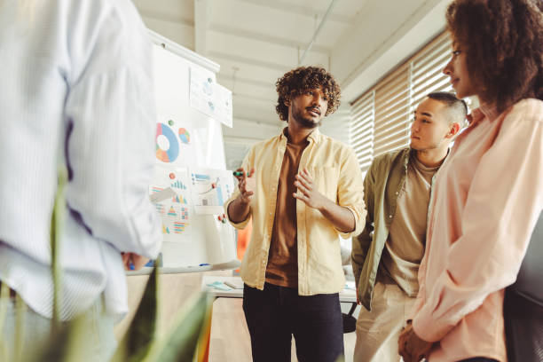 istock Young manager explaining charts on whiteboard to colleagues 2180338190