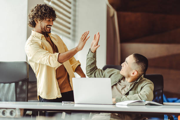 istock Two male colleagues giving high five celebrating success at office 2180342445