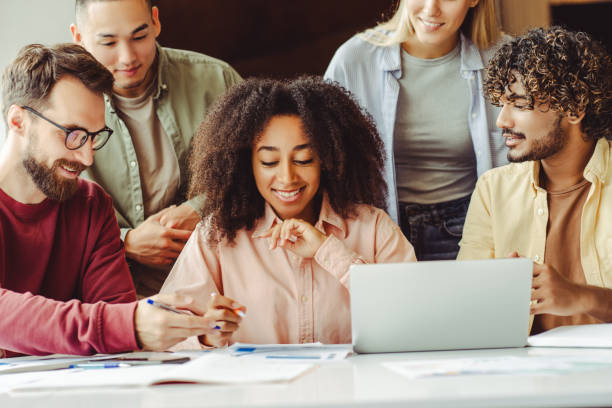 istock Diverse team of young professionals working together on a project using laptop 2180342471