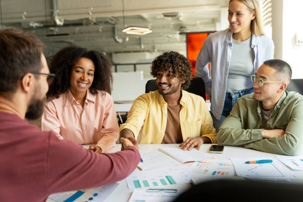 istock Diverse team celebrating success around a table with charts and graphs 2180342493