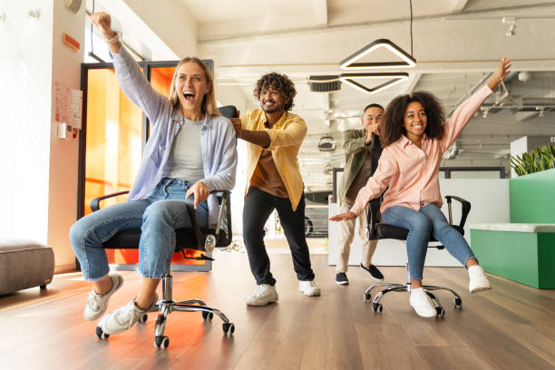 istock Excited business people having fun racing on office chairs 2180342507