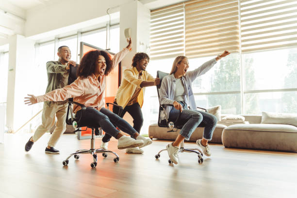 istock Young multicultural business team having fun racing on chairs in office 2180342511