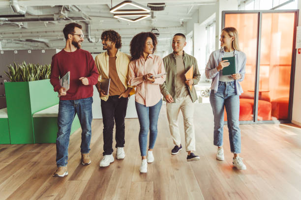 istock Diverse team of young professionals walking through office corridor 2180342518