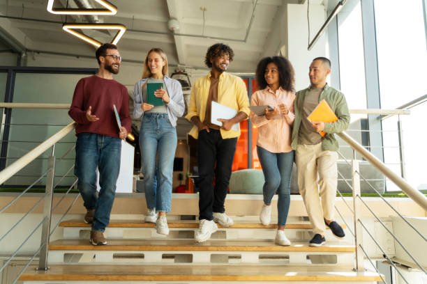 istock Diverse business team walking downstairs in modern office building 2180342524