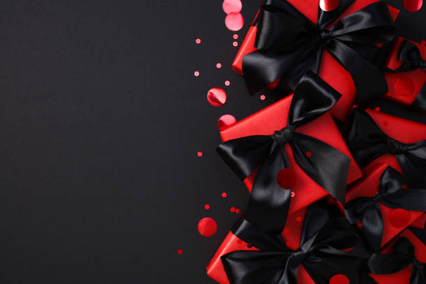 istock Black Friday sale concept. Elegant black gift boxes with red ribbons on a dark background 2180342721