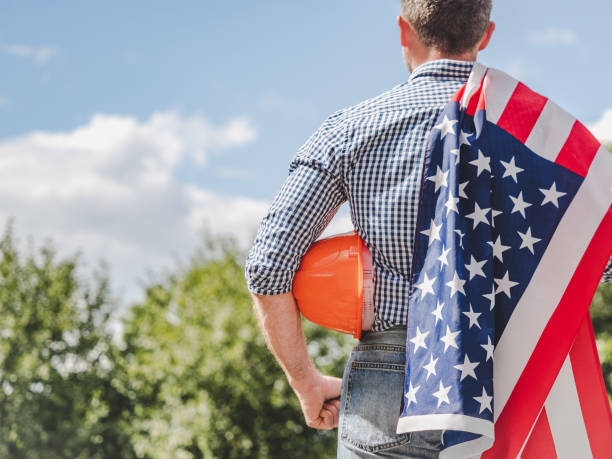 istock Attractive man in work clothes holding American Flag 2180348542