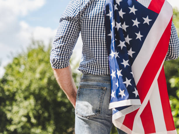 istock Attractive man in work clothes holding American Flag 2180348650