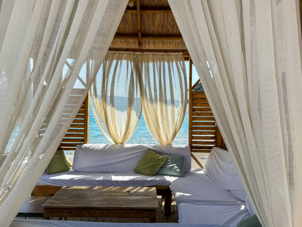 istock Cozy beach cabana with white curtains overlooking the ocean at sunset on a serene evening 2180351206