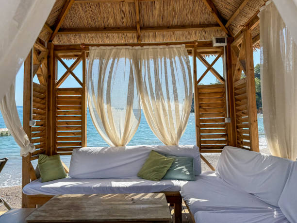 istock Cozy beach cabana with white curtains overlooking the ocean at sunset on a serene evening 2180351423