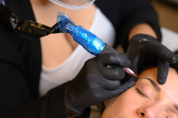 istock Beautician applying permanent eyebrow makeup with microblading machine on brunette hispanic 30 woman 2180372951