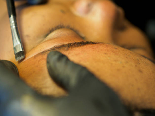 istock Beautician preparing eyebrow with white marker before permanent makeup on young african woman 2180378818