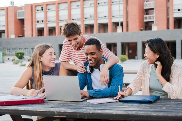 istock Group of young classmates studying together and preparing a exam using a laptop, browsing on internet at university campus. Teenage students smiling and doing the homeworks with a notepad computer 2180383474