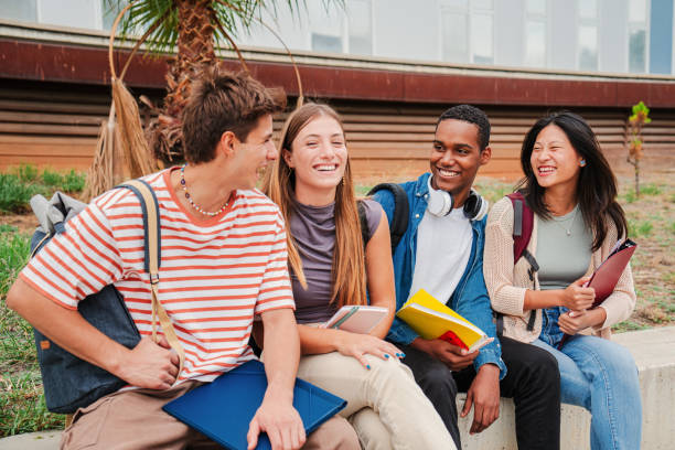 istock Group of multiracial young academic students talking together sitting at university campus. Classmates having a friendly conversation at highschool. Portrait of happy teenagers laughing and having fun 2180384958