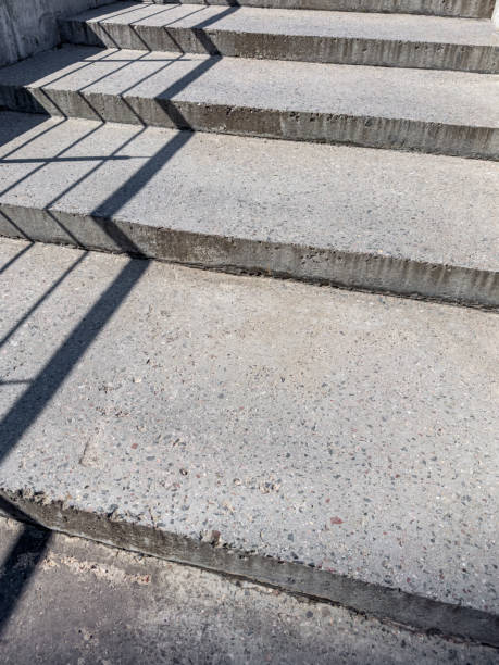 istock concrete steps of a ladder with a shadow from a metal handrail. 2180387928