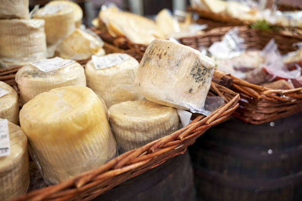 An extensive array of cheeses on display on a stall in Borough Market in Southwark, London, a famous tourist attraction.