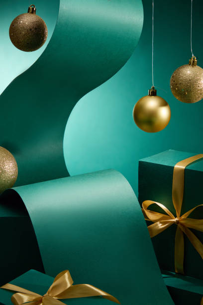 istock An opulent emerald backdrop with a Christmas motif, showcases empty product display stands adorned with gold-ribbon-wrapped green present boxes, green wavy paper, and Noel balls. 2180388749