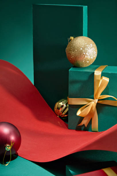 istock The Christmas concept image template, with the product display space placed on winding paper roll, surrounded by green cubes and decorated with red and gold Noel balls. 2180388779