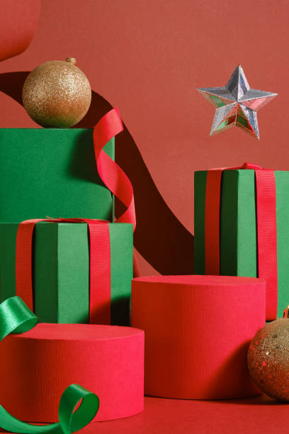 istock Christmas concept features a set of red cylindrical podiums, arranged on the red surface, next to green rectangle podiums with star and baubles. Empty space on the podium for product presentation. 2180389527