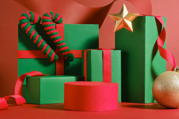 istock The empty red platform is surrounded by green rectangles tied with red ribbons, decorated with Christmas balls, wool candy canes, and red paper strips. Sample image displaying Christmas products. 2180389534