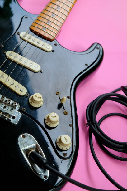 istock Black electric guitar on pink background 2180394529