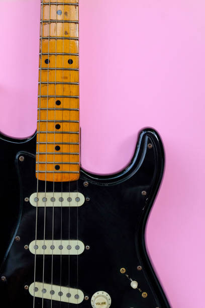 istock Black electric guitar on pink background 2180394553